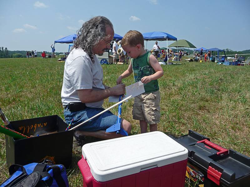 Carl assembling Matthew's rocket.<br />A Central Massachusetts Spacemodeling Society (CMASS) event.<br />July 17, 2010 - Woodsom Farm, Amesbury, Massachusetts.