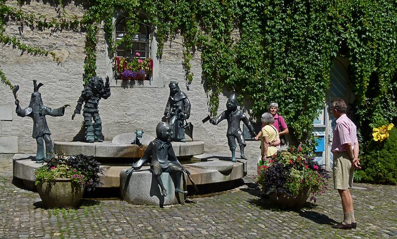 Joyce, Heidi, and Karl looking at carnival stautes around a fountain.<br />August 2, 2011 - Lindau, Bavaria, Germany.