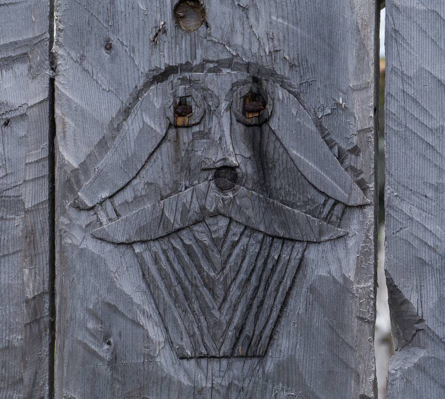 A carving in the fence.<br />July 9, 2012 - Norstead Viking Village, L'Anse aux Meadows, Newfoundland, Canada.