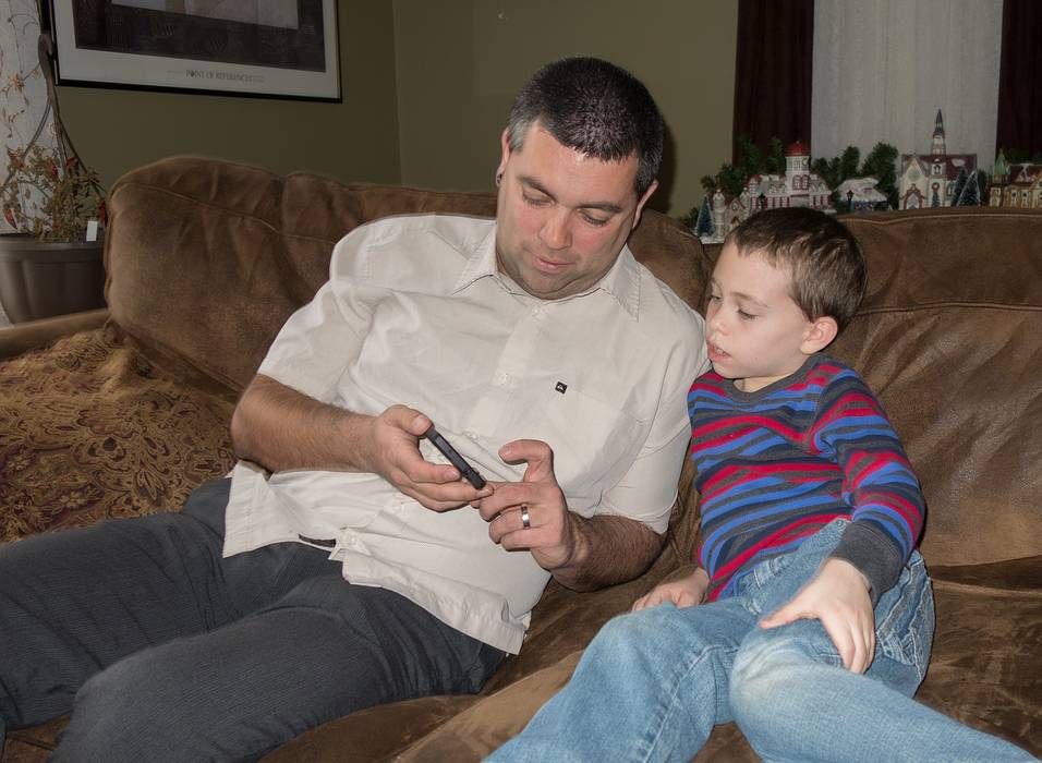 Sati showing Matthew something on his phone.<br />Dec. 26, 2013 - At Carl and Holly's in Mendon, Massachusetts.