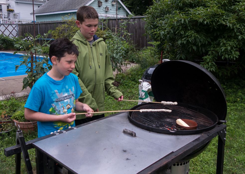 Marks and Zachary baking dough on a stick.<br />July 19, 2014 - At Marie's in Lawrence, Massachusetts.