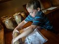 Matthew crushing crackers in the pantry of the 1890 Farm House.<br />July 14, 2015 - Biliings Farm and Museum in Woodstock, Vermont.