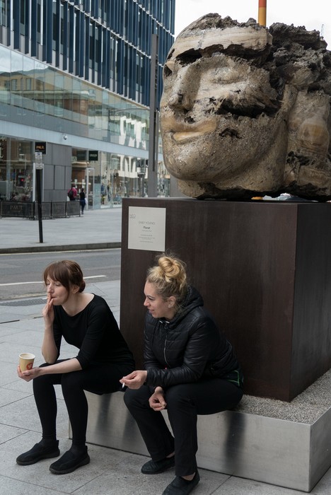 An Emily Young sculpture and two young English women smoking.<br />May 22, 2016 - London, UK.