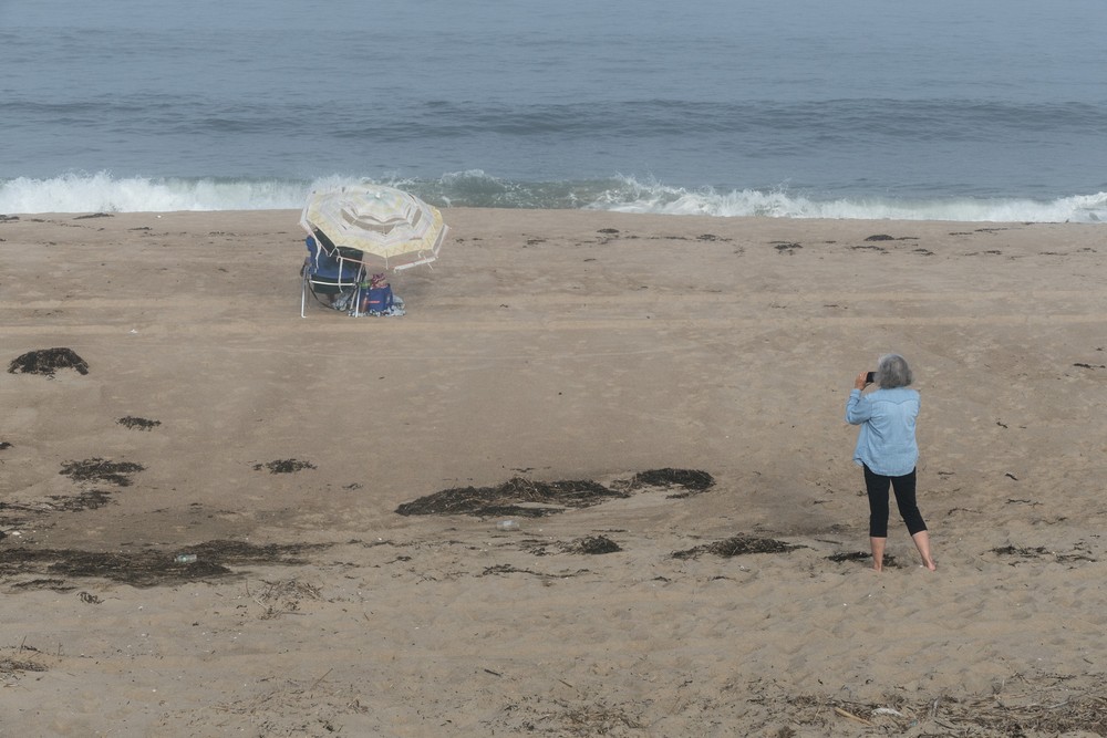 Joyce photographing woman under tattered umbrella.<br />Sept. 8, 2016 - Parker River National Wildlife Refuge, Plum Island, Massachusetts.