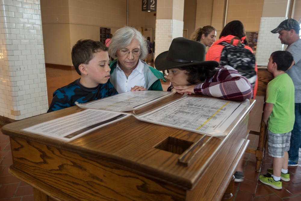 Matthew, Joyce, and Miranda looking at a passenger list in the Great Hall of the main building on Ellis Island.<br />July 13, 2017 - Manhattan, New York City, New  York.