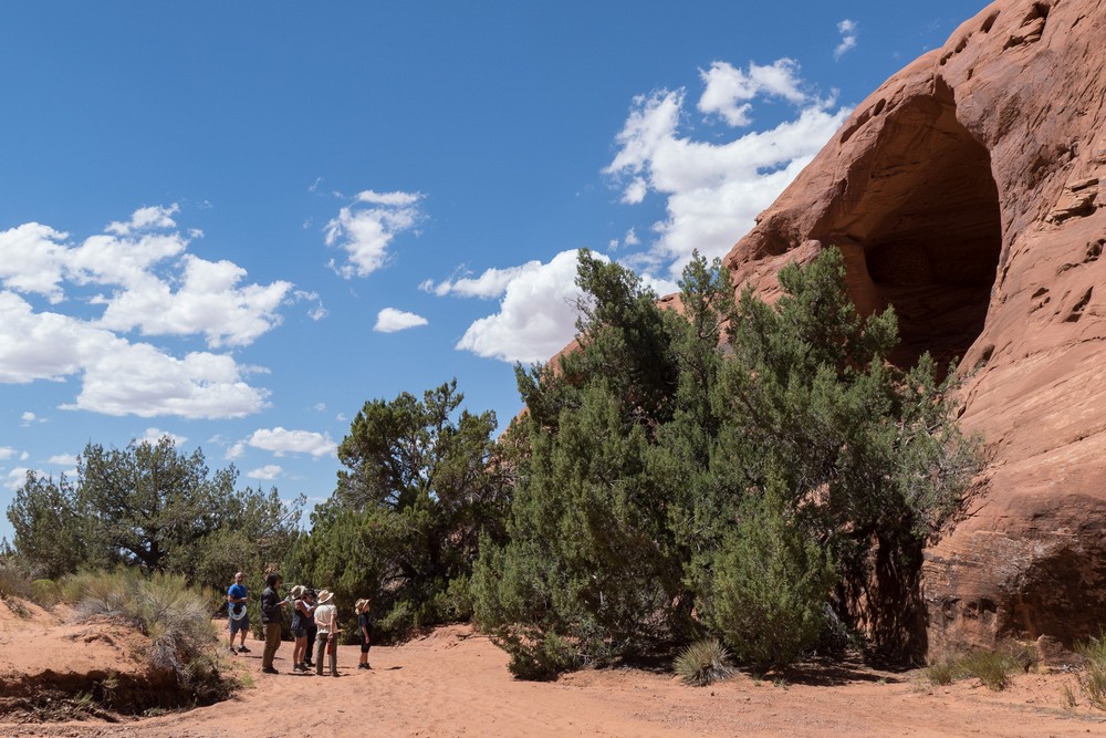 Carl, Sean, Holly, Miranda, Joyce, and Matthew looking at a big hole in the rock (it has some Anasazi structures inside)).<br />On tour with Navajo Spirit Tours.<br />Aug. 14, 2017 - Monument Valley Navajo Tribal Park, Arizona.