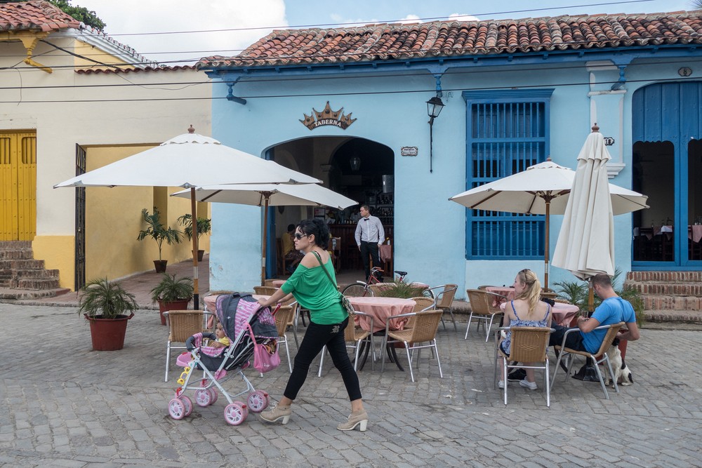Woman with child in carriage in front of a restaurant.<br />Plaza de San Juan de Dios.<br />Nov. 3, 2016 - Camag�ey, Cuba.